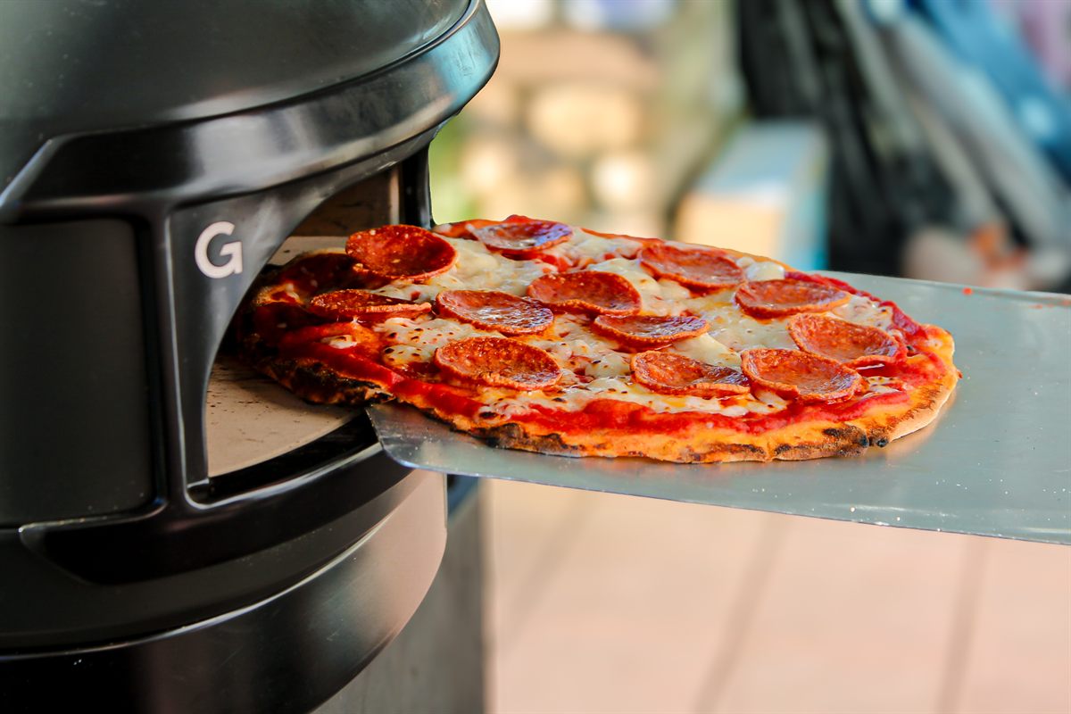 Chef Kaynan pulling a fresh pizza out of the Gozney wood-fired oven