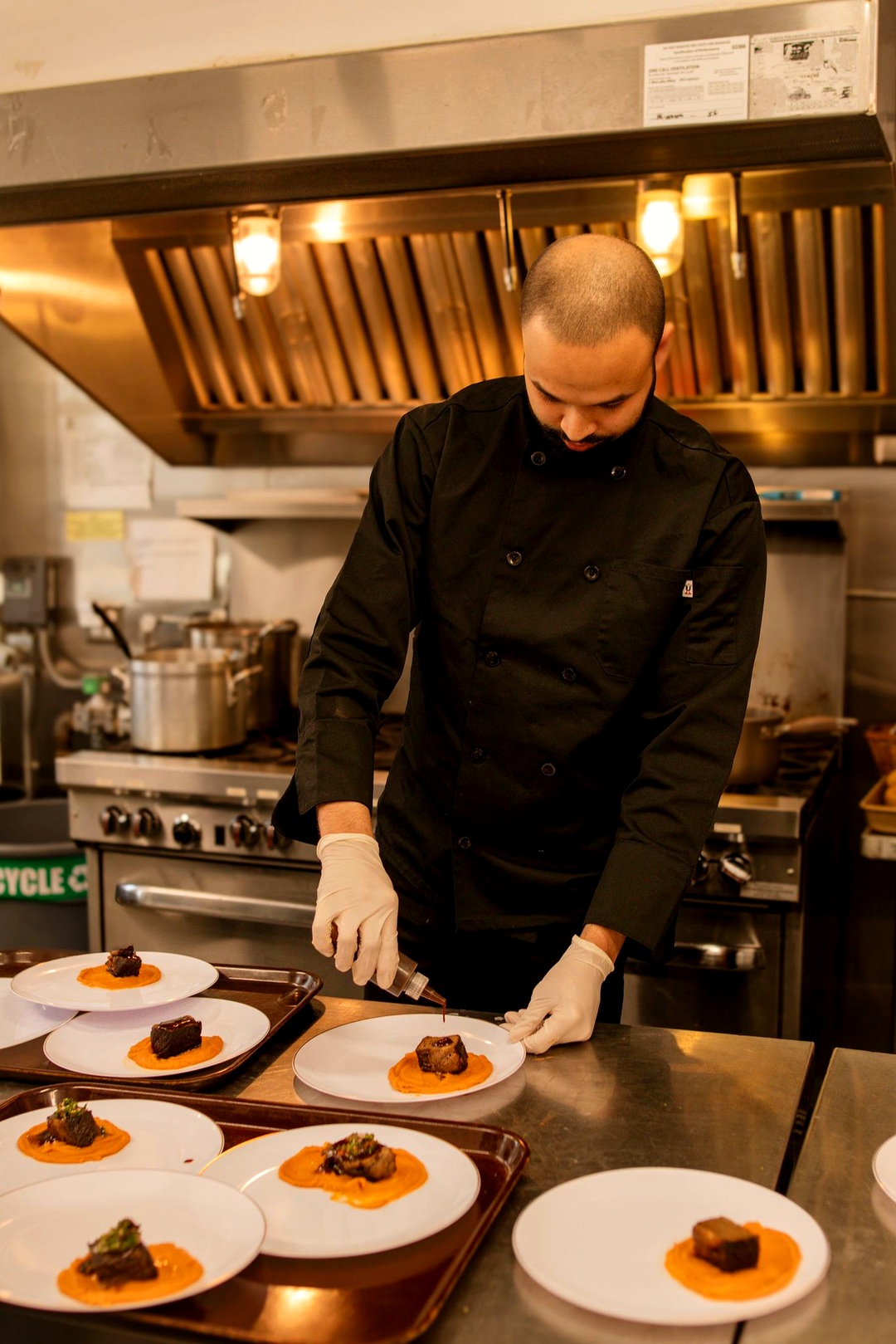 Chef Kaynan plating a fine dining dish in a commercial kitchen