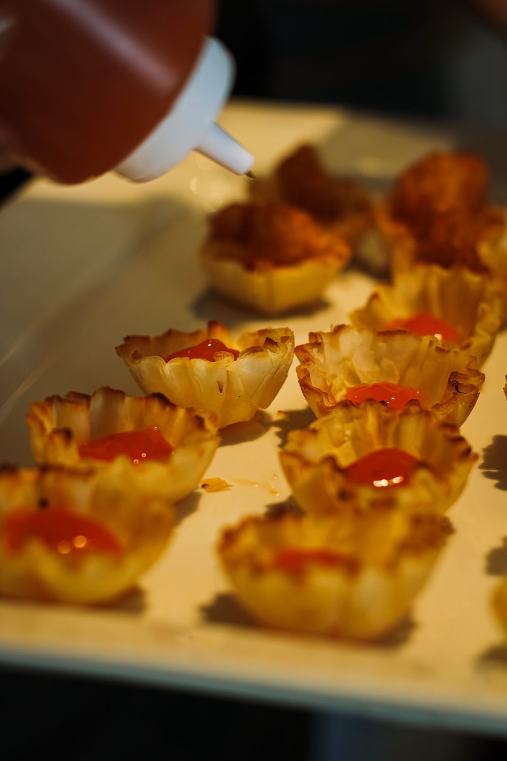 Finishing phyllo cup canapes with sauce before service