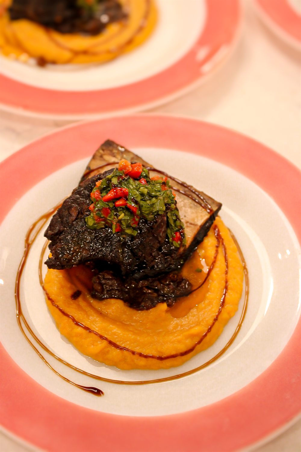 Braised short rib with sweet potato puree and chimichurri, plated for a private dinner