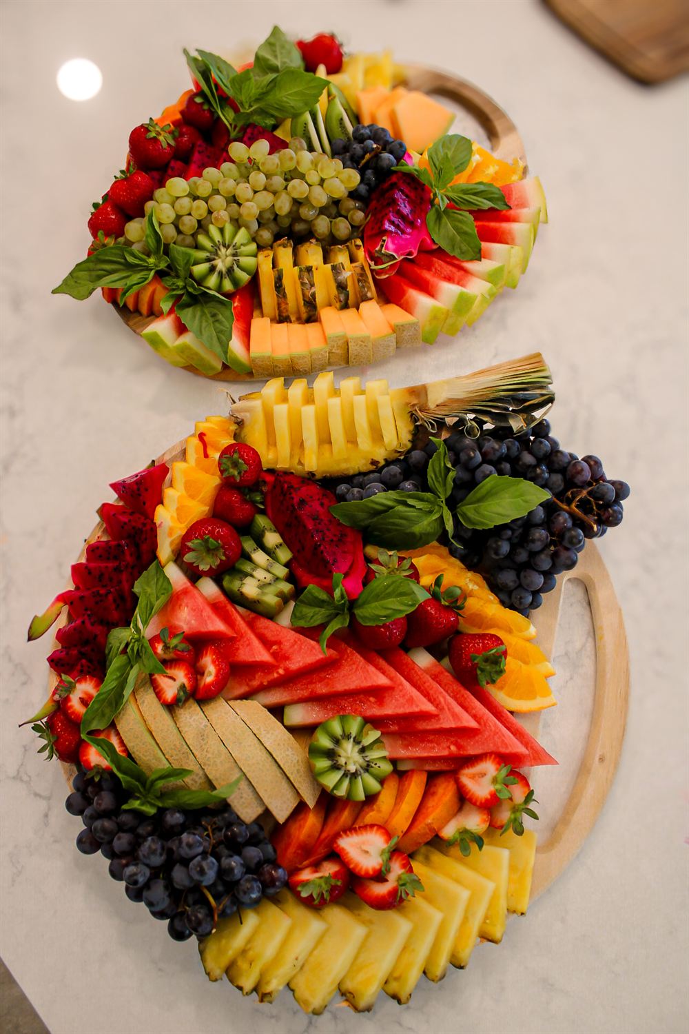 Two tropical fruit boards with dragon fruit, pineapple and basil